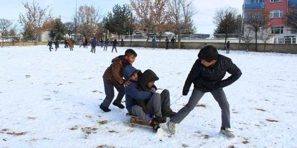 Early adolescent boys sledding in new snow with an urban background