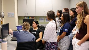 Image for Students at the 2025 Summer Research Bootcamp stand around an MRI brain scan